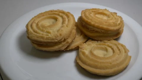 A small stack of round butter cookies with a spiral pattern rotates slowly .. Stock Footage 328485765