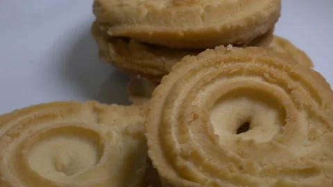 A small stack of round butter cookies with a spiral pattern rotates slowly .. Stock Footage 328485795