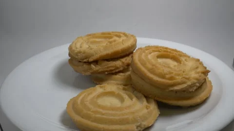 A small stack of round butter cookies with a spiral pattern rotates slowly .. Stock Footage 328485848