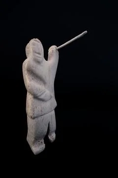 Small statue of Inuit hunter with a spear made of animal bone. Isolated on black Stock Photos