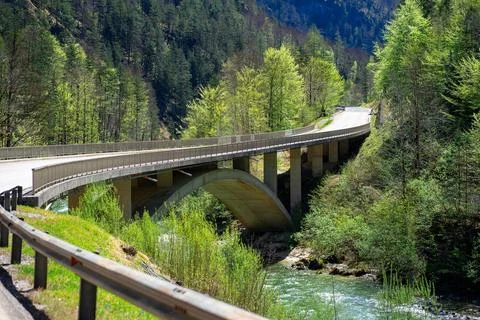 A small stone bridge over a mountain river in the Austrian Alps on a sunny da Stock Photos