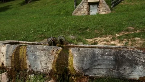Small stone cellar for water source with metal door on alpine meadow in South Stock Footage 315007891