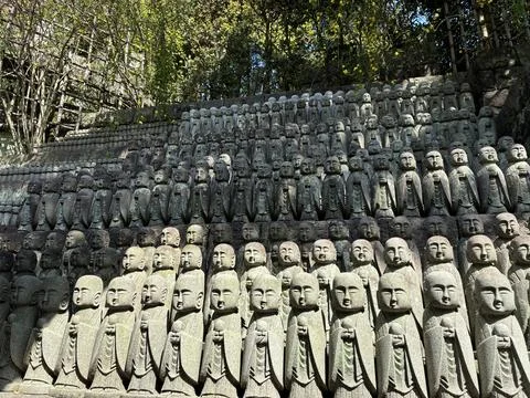 Small stone Jizo statues lined up in rows on a hillside at the historic Hasedera Stock Photos