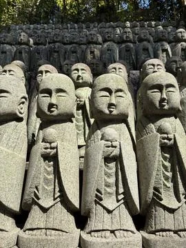 Small stone Jizo statues lined up in rows on a hillside at the historic Hasedera Stock Photos