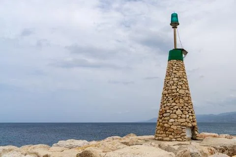 Small stone lighthouse on pier extending into sea in Cyprus. Coastal naviga.. 库存照片