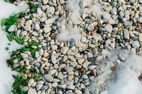Small stone pebbles in a flower bed covered with snow. small stones for gar.. Stock Photos