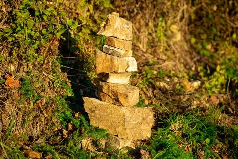 Small stone pyramid on a background of stone and green ivy Foto stock