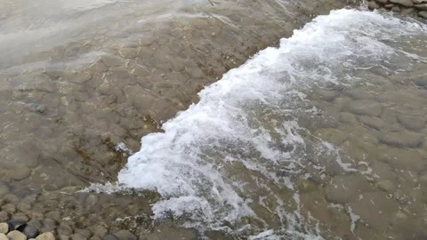 A small stone threshold on a mountain river. Strong water flow with splashes and 库存影片 251995339