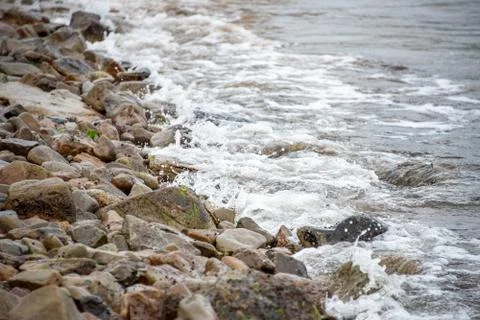 Small stones on the seashore, the rolling waves of the sea with foam Stock-Fotos