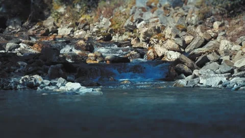 A small stream cascading over the rocky shore falls in the Naeroy Fjord. Stock Footage 280227982