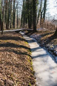 A small stream covered with ice in winter with a concrete bridge Stock Photos