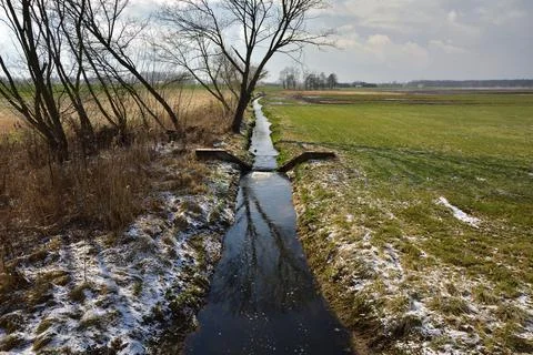 A small stream divided by a concrete dam, a sunny spring day. Stock Photos