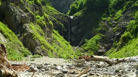 A small stream is flowing in front of a slim waterfall in a beautiful scenery. 스톡 동영상 211499652