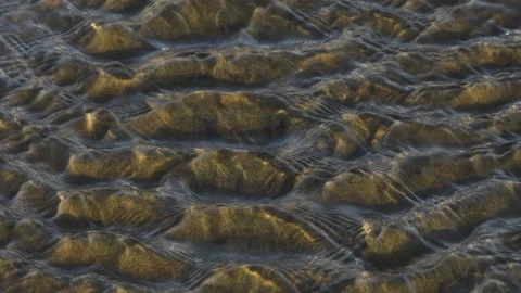 A small stream flows across a sandy beach, a study of motion and pattern Video stock 170253953