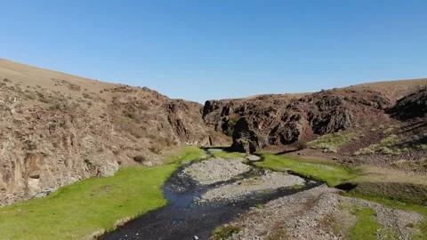 A small stream flows through a rocky canyon in a desert area Stock Footage 232375076