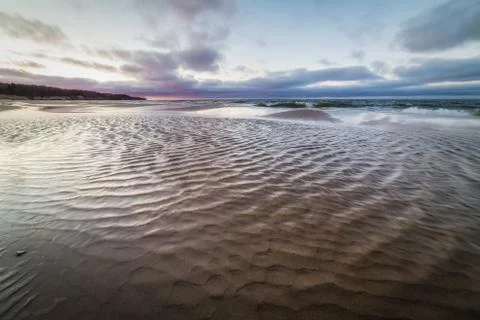 Small stream flows into the waters of the Baltic sea at sunset Stock Photos