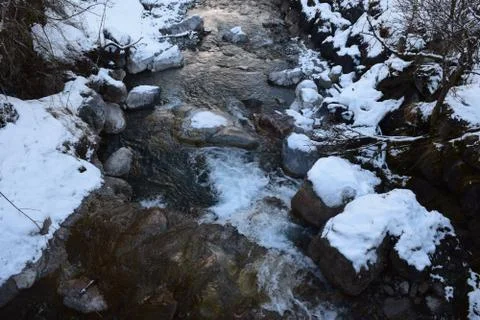 A Small Stream Running down a Snow Covered Mountain Stock Photos
