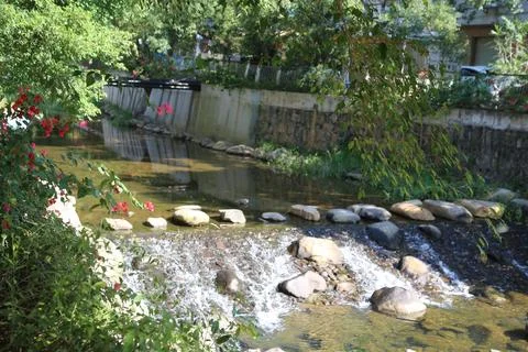 A small stream with a stone wall on the side Stock Photos