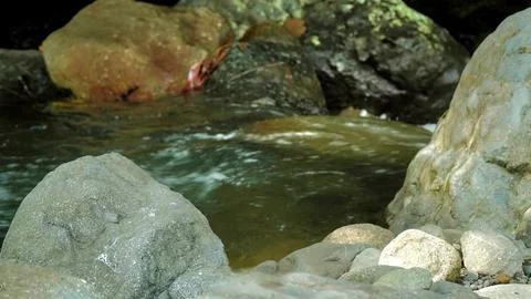 A small stream of water flows between two large rocks Stock Photos