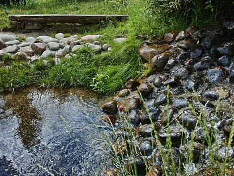 A small stream of water flows between two rocks Stock Photos
