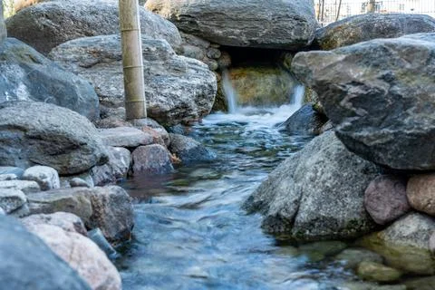 A small stream of water flows between large rocks Stock Photos