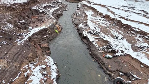 A small stream winds through a dried lakebed covered in snow, as seen from .. Stock Footage 297548515
