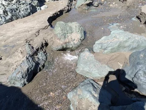 A small stream winds through sand and stones on a beach 库存照片