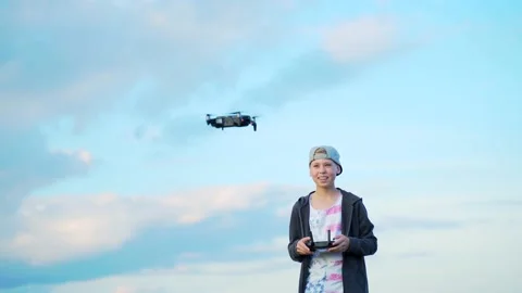Small stylish boy in a cap launches a drone into the sky outside.yf Stock Footage 138601348