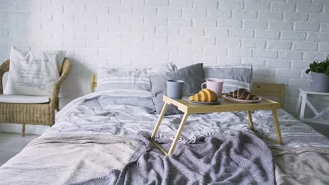 Small table with coffee and croissants on large bed in flat Stock Footage 137292361