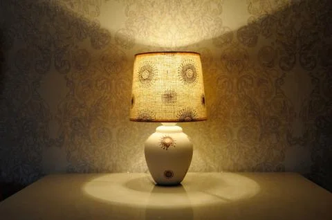 A small table lamp, with a yellow light on the bedside table Stock Photos
