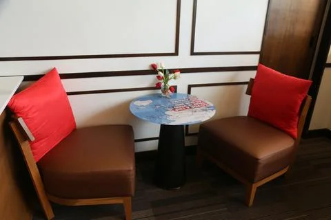 A small table with a world map on it is placed between two brown leather ch.. Stock Photos