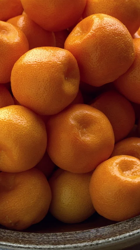 Small tangerines in a bowl. Table  spin. Seamless loop. Vertical video. Stock Footage 277607712