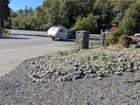 A small T&amp;B teardrop camper being towed along a forest road Stock-Fotos