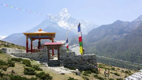 Small temple at the slope surrounded by huge mountains and prayer buntings Stock Footage 77449844