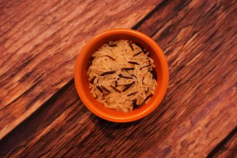 Small terracotta pot of wild rice on dark wooden background Stock Photos