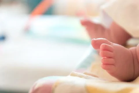 The small tiny cute feet of the infant. Blurred light background Stock Photos