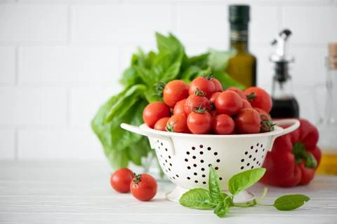 Small tomatoes in a colander with basil and spices Stock Photos