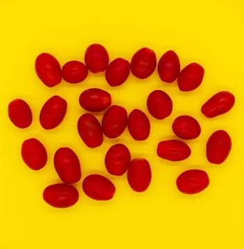 Small tomatoes isolated on yellow background Stock-Fotos