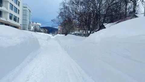 Small town buried in deep snow after massive blizard. Cleared road after a snow Stock Footage 263177348