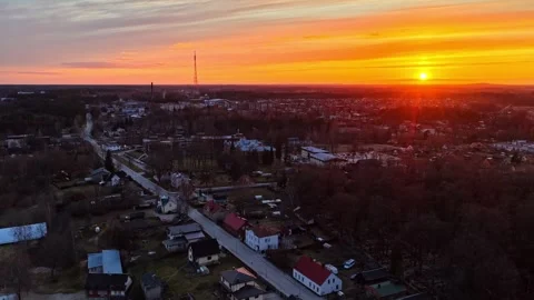 Small town with dramatic orange sunset and glowing sun on the horizon Stock Footage 336289846