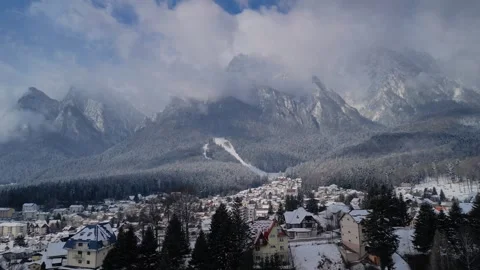 A small town at the foot of Bucegi Mountain seen from a drone on a snowy day 4k Stock Footage 293311024