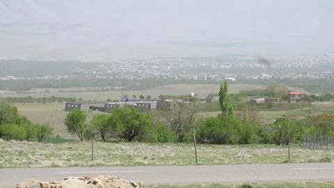 A small town with green fields and distant mountains, stock photo. Stock Photos