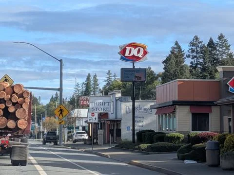 Small-town main road with logging truck ahead, Dairy Queen Фото
