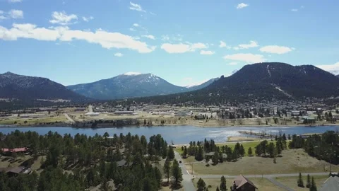 A small town sits beneath large snow capped mountains from drone Video stock 167675176