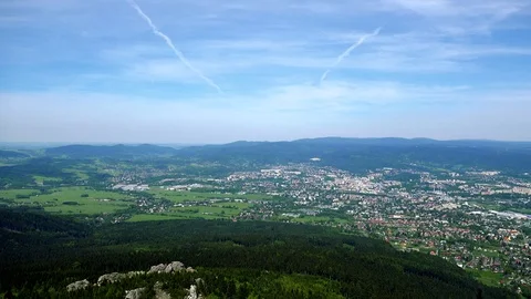 A small town surrounded by a forest, the bright blue sky in the background - top 스톡 동영상 73415055