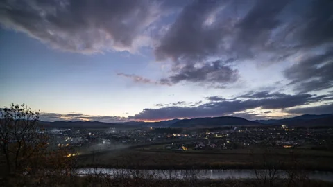 Small town turns on lights under dark evening sky at sunset Stock Footage 181137966