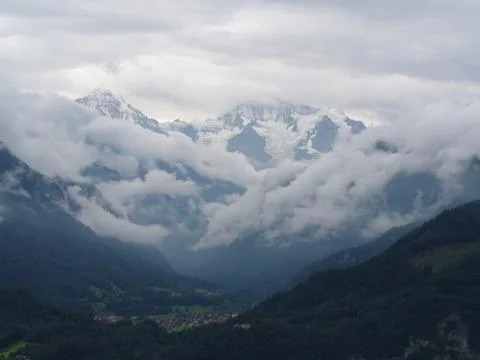 Small town under the mountains in clouds Stock Photos