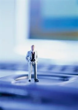 Small toy figure standing on computer keyboard, focus on figure 스톡 사진