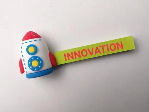 A small toy rocket attached to a yellow strip labeled INNOVATION lies on a .. Stock Photos