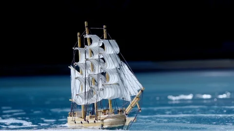 Small toy ship with sails is floating on waves in pool, moving by underwater Stockbeeldmateriaal 103830335